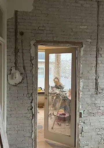Voor: kale bakstenen wand met doorbraak, klaar voor afwerking